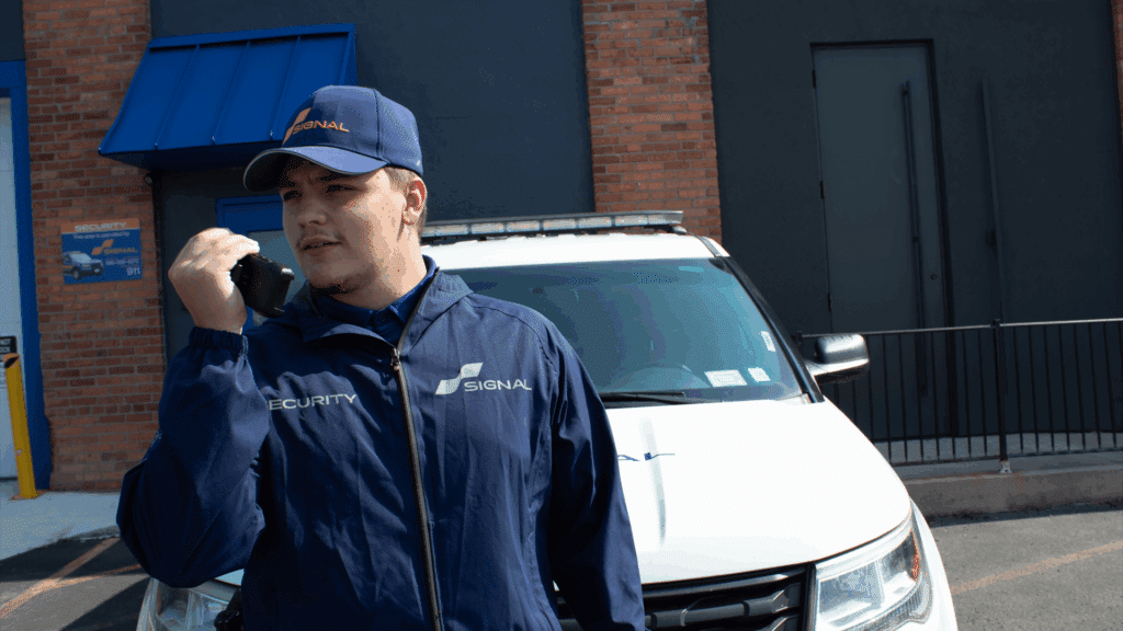 Security officer communicating by radio in front of Signal patrol vehicle